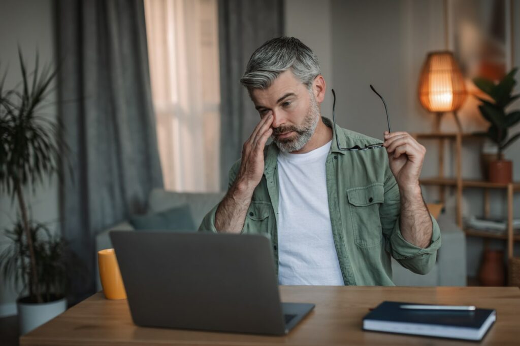 Man sitting in front of a laptop suffering from dry eye