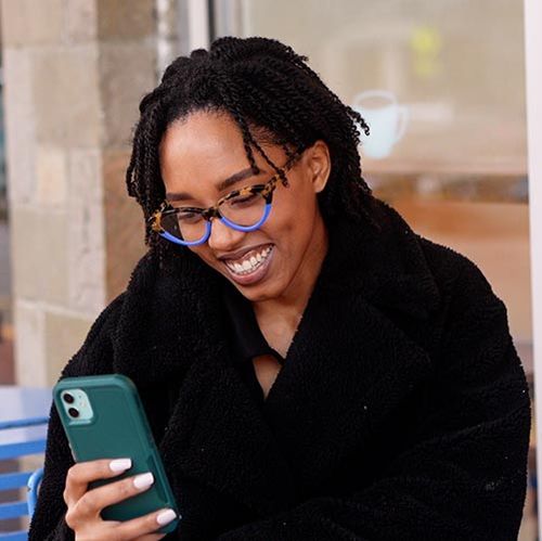 woman wearing glasses on phone changing her flexible vision correction appointment